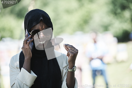 Image of african woman using smartphone wearing traditional islamic clothes