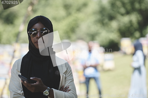 Image of african woman using smartphone wearing traditional islamic clothes