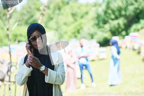 Image of african woman using smartphone wearing traditional islamic clothes