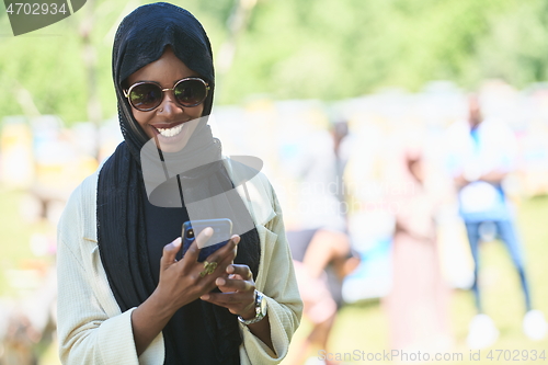 Image of african woman using smartphone wearing traditional islamic clothes