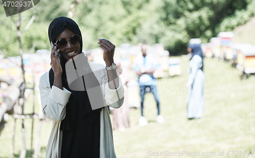 Image of african woman using smartphone wearing traditional islamic clothes