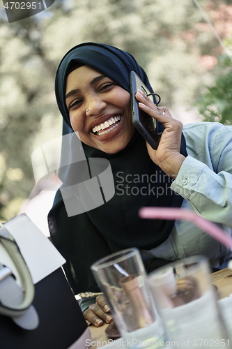 Image of african woman using smartphone wearing traditional islamic clothes