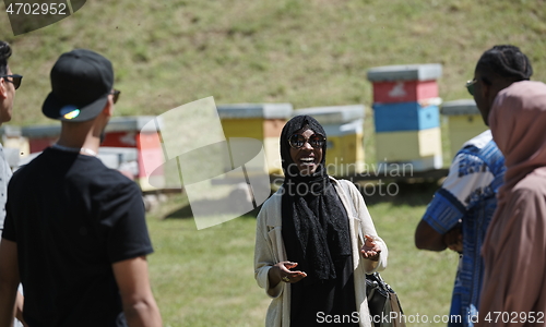 Image of woman giving presentation to group of business investors on local honey production farm