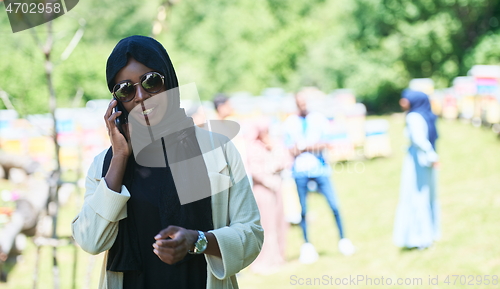 Image of african woman using smartphone wearing traditional islamic clothes