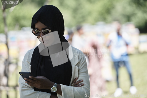 Image of african woman using smartphone wearing traditional islamic clothes