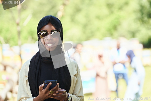 Image of african woman using smartphone wearing traditional islamic clothes