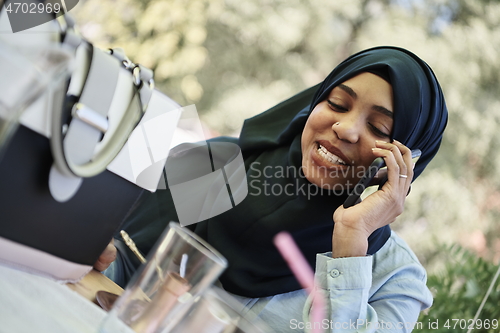 Image of african woman using smartphone wearing traditional islamic clothes