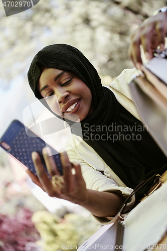 Image of african woman using smartphone wearing traditional islamic clothes