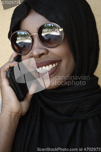 Image of african woman using smartphone wearing traditional islamic clothes