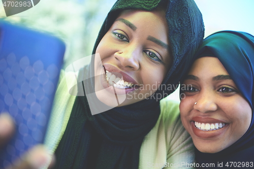 Image of african female friends using smart phone together