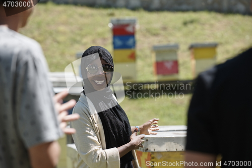 Image of woman giving presentation to group of business investors on local honey production farm