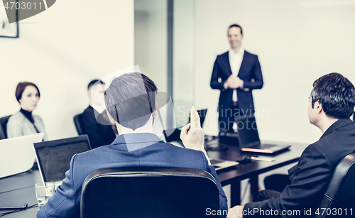 Image of Successful team leader and business owner leading informal in-house business meeting. Businessman working on laptop in foreground. Business and entrepreneurship concept