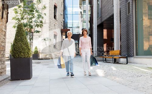 Image of senior women with shopping bags walking in city