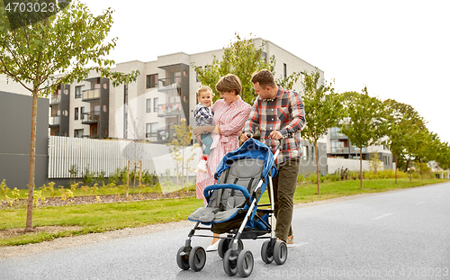 Image of family with baby and stroller walking along city