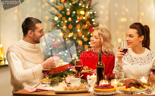 Image of happy friends having christmas dinner at home