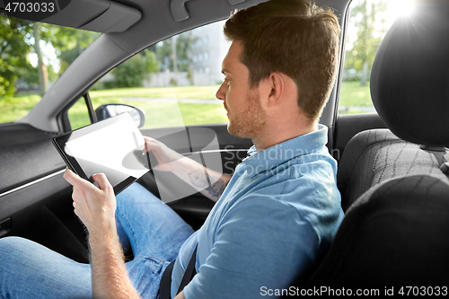 Image of male passenger using tablet computer in taxi car