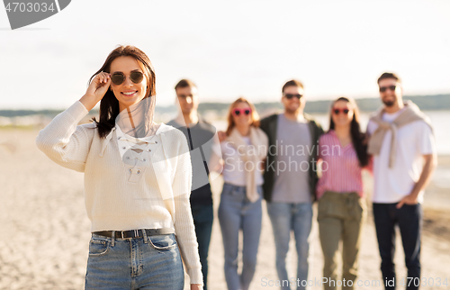 Image of happy woman with friends on beach in summer