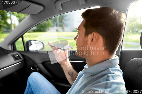 Image of passenger recording voice on smartphone in car