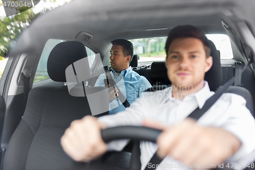 Image of male passenger with smartphone and car driver