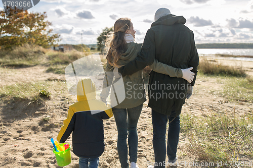 Image of happy family walking along autumn beach