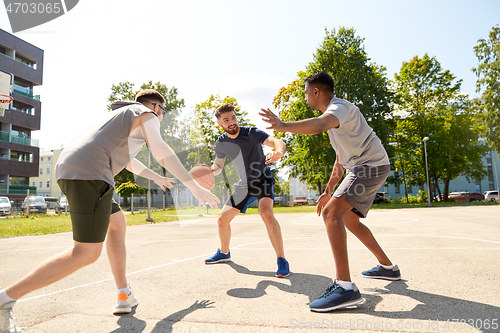 Image of group of male friends playing street basketball