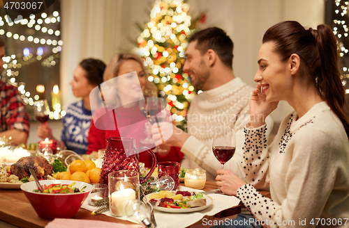 Image of happy friends having christmas dinner at home