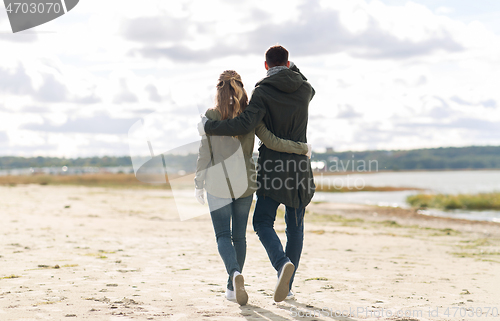 Image of couple walking along autumn beach and hugging