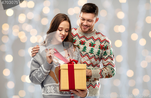 Image of happy couple in christmas sweaters with gift box