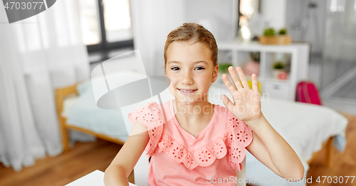 Image of happy little girl waving hand at home