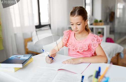 Image of student girl with book writing to notebook at home