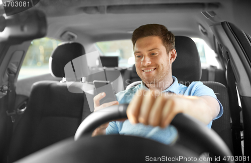 Image of man driving car and using smartphone