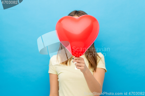 Image of woman covering face with heart-shaped balloon