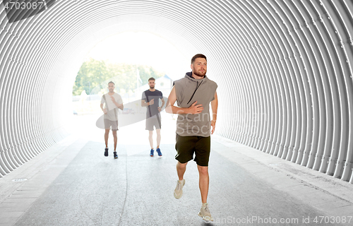 Image of young men or male friends running in tunnel