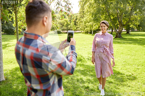 Image of couple photographing by smartphone in park