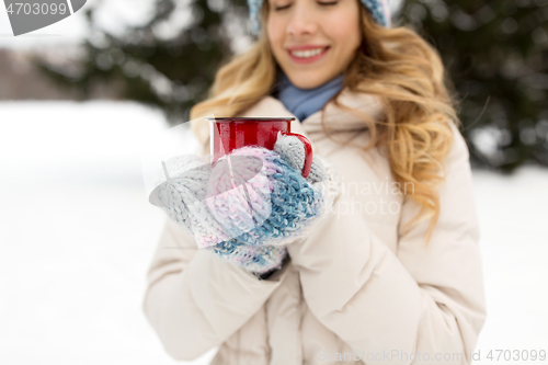 Image of happy young woman with tea cup in winter park