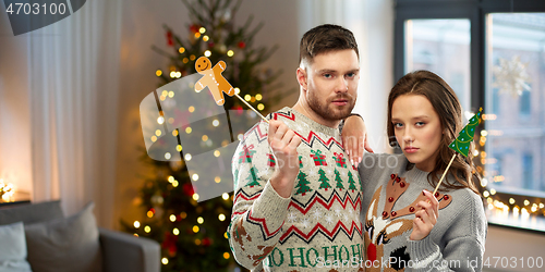 Image of couple with christmas party props in ugly sweaters