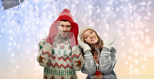 Image of couple in ugly sweaters and mittens on christmas