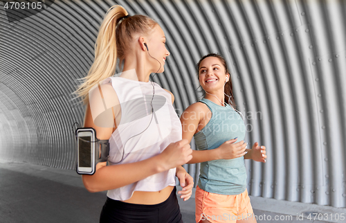 Image of young women with earphones and smartphones running