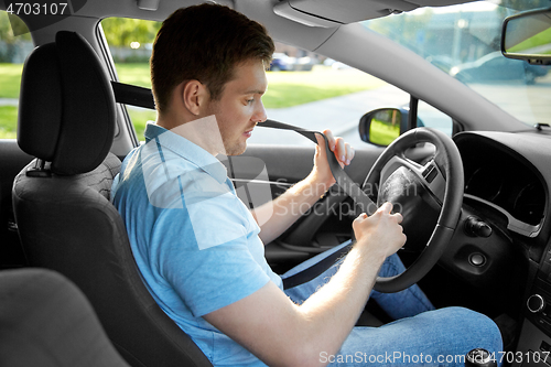 Image of man or car driver fastening seat belt