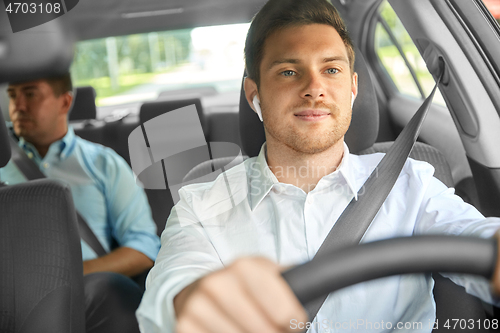 Image of male driver with wireless earphones driving car