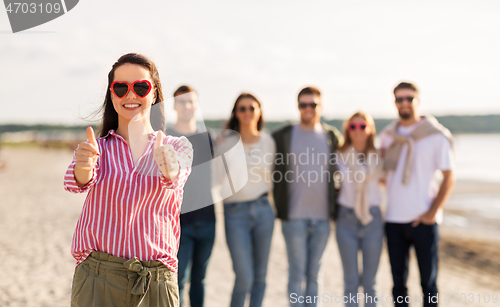 Image of woman with friends on beach showing thumbs up