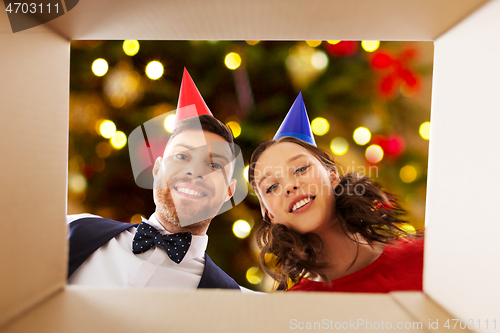 Image of couple in party hats opening birthday gift box