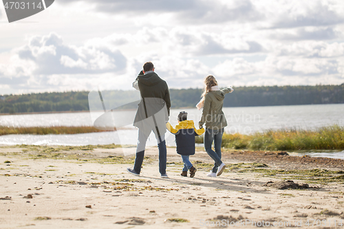 Image of happy family walking along autumn beach