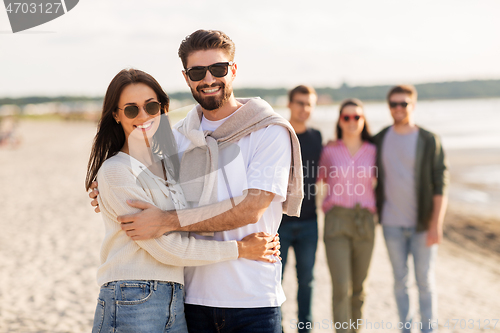 Image of happy couple with friends on beach in summer