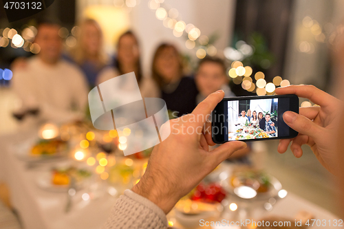 Image of man taking picture of family at dinner party