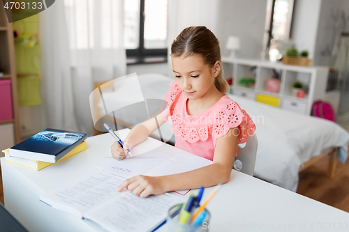 Image of student girl with book writing to notebook at home