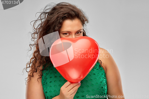 Image of playful woman holding red heart shaped balloon