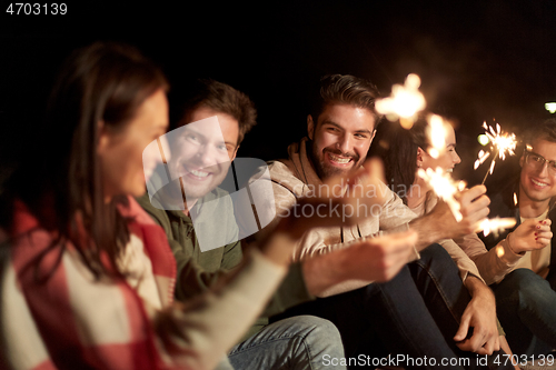 Image of happy friends with sparklers at night outdoors