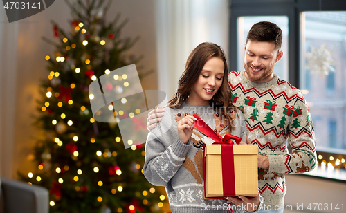 Image of happy couple in christmas sweaters with gift box