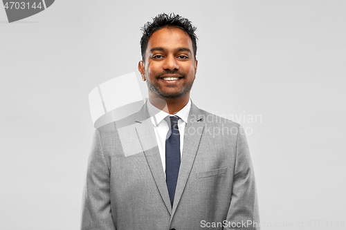 Image of smiling indian businessman over grey background